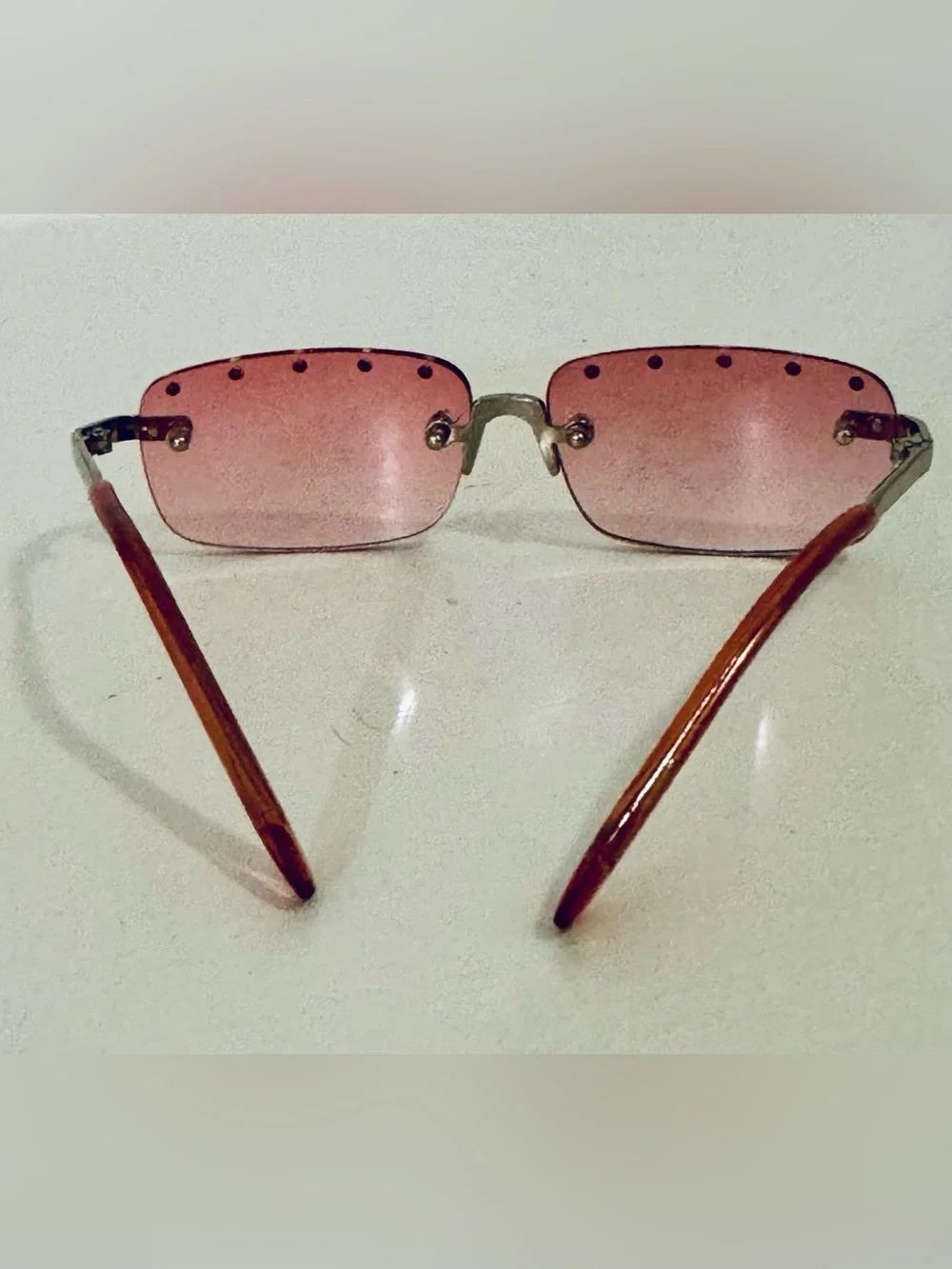 Stylish pink rimless sunglasses adorned with decorative rhinestones. These glass